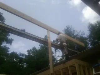 Carpenter setting a ridge beam over a new addition frame — Ice Dam Removal by Roofing Brothers in Bee